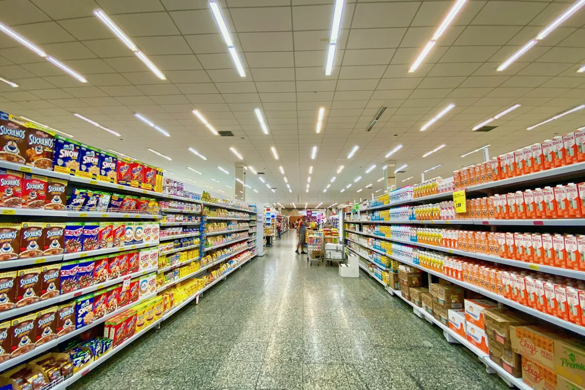 Retail store aisle with shelves stocked with packaged goods under bright lights