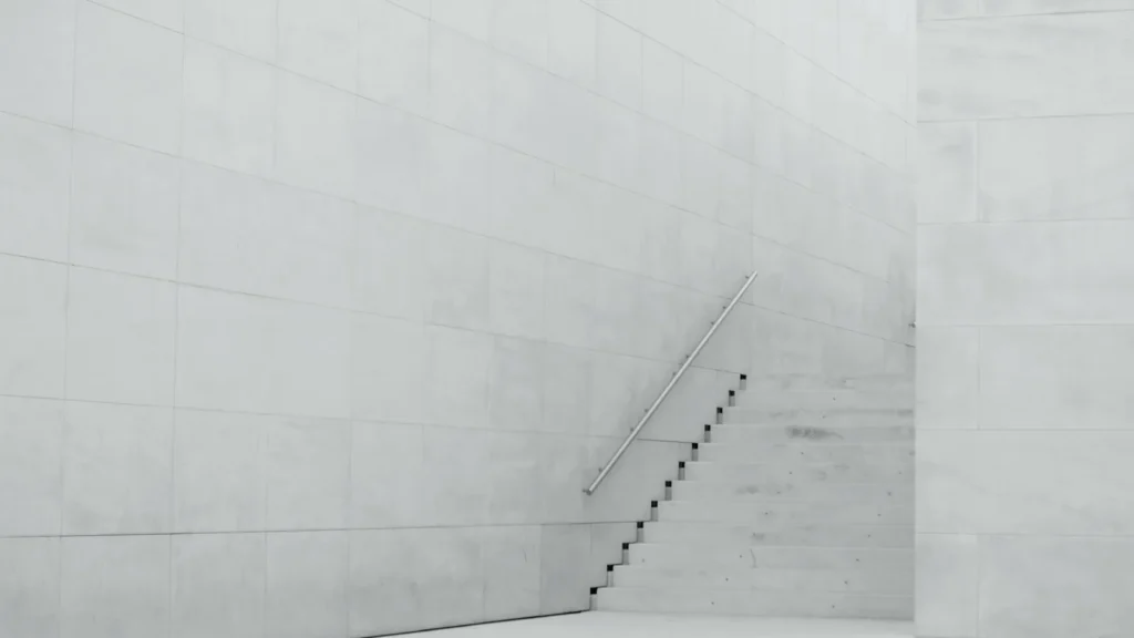 White concrete steps rising toward a bare wall, fading into bright light