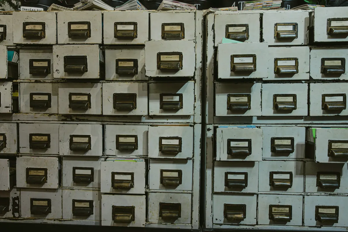 Wall of small labeled filing drawers in a records room