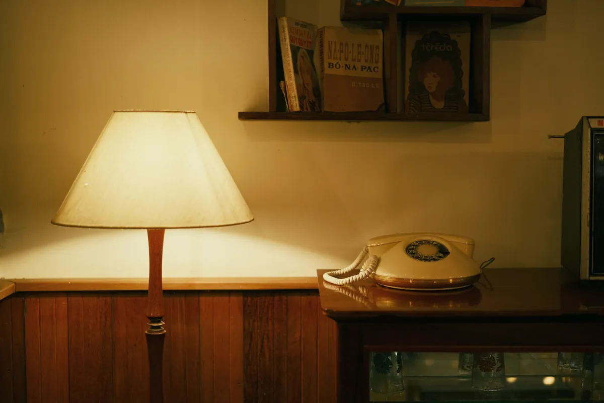 Rotary telephone beside a glowing table lamp in a warmly lit room