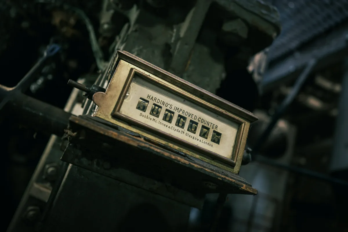 Handheld metal tally counter resting on a neutral background
