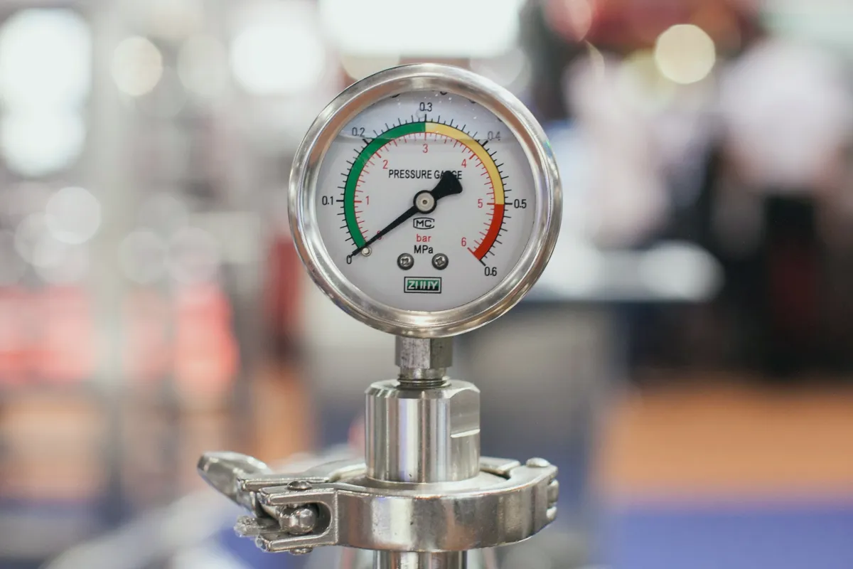 Dial pressure gauge mounted on industrial piping showing system line pressure